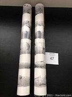 Two rolled birch tree wallpaper rolls standing upright, sealed with tape.