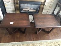 Both walnut side tables positioned side by side in front of fireplace