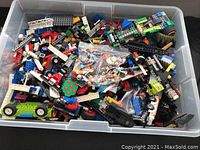 Photo of plastic bin filled with assorted loose LEGO bricks and parts of various colors and types.