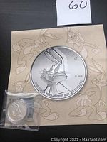 Front of coin showing Bugs Bunny and inscriptions with card background of Bugs Bunny sketches.
