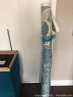 Tall vertical roll of fabric wrapped showing multicolor leaf pattern on a neutral background.