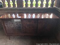 Front view of vintage veneer buffet showing the glass sliding door with mirror backing, drawers with two missing pulls, and veneer finish.