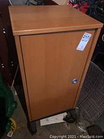 Closed IKEA wooden cabinet on black caster wheels showing front door with metallic handle.