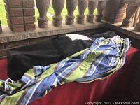 Free standing hammock folded inside black carrying bag with striped fabric hammock partially visible.