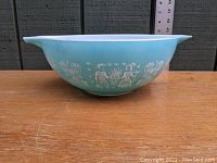 Side view of blue Pyrex Amish Butterprint bowl showing white design details and size compared to ruler