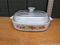 Casserole dish with Spice of Life pattern on the side and clear glass lid on top, shown from side view