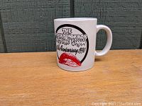 Side view of white ceramic mug with Rocky Horror Picture Show 15th Anniversary 1990 print and red lips graphic, showing handle and print details.