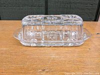 Side view of the glass butter dish with lid on wooden surface