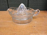 Full view of the clear glass orange reamer showing the criss cross pattern and the pouring spout