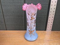 Front view of Victorian blown satin glass vase showing pink to blue gradient and gilt foliate design with ruffled rim and ruler for scale.