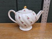 Side view of white Sadler porcelain teapot with pink rose decals and gold accents, showing elegant curved handle and lid with gold knob.