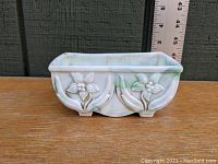 Front view of the rectangular glass planter showing floral relief and marbled green and white pattern, with ruler in background for scale.