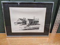 Photo of framed black and white pen and ink print showing Saugus Iron Works with water wheels and buildings.