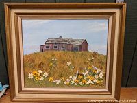 Full view of framed oil painting showing the red barn behind a dense field of grass and flowers
