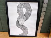Full view of framed pencil drawing showing surrealist image of a man entwined inside a large serpent with textured scales