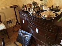 Wide view of dining room sideboard with numerous silver plate and sterling pieces arranged on top.