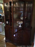 Front view of entire cabinet showing upper glass door display and lower drawer and cabinet sections.