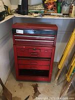 Red two-piece metal tool cabinet with multiple drawers showing some wear and dirt on the surface.