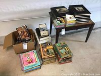 Wide view of all books, boxed games, and photo albums arranged on floor and bench, showing general condition and quantity
