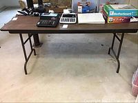 Folding table with various items placed on top showing overall appearance and dimensions.