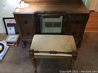Full view of wooden dressing table with central drawer and side storage compartments, paired with upholstered stool placed in front.