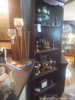 Full view showing wooden shelving unit holding gnome figurines, metal candle holders, vases, photograph holder, and decorative cups.