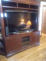 Full view of Samsung TV in wooden entertainment center, shows overall size and placement