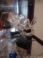 Clear Frabel glass art piece with flowers and bird on black base displayed in curio cabinet