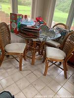 Full view of glass top table with four rattan chairs around it, showing table top and chair seats.