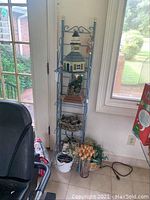 Full view of tall blue metal shelving unit holding lighthouse table fountain and decorative items on the shelves and floor beneath