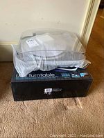 Turntable stored on original box with dust cover on top.