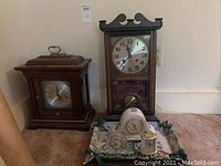 Photo showing all 5 clocks together including the Howard Miller desk clock, the tall wall clock missing top finials, and three smaller clocks on a tray.