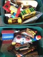 Image showing bin with vintage Fisher-Price plastic and wooden toy vehicles including yellow bus with green sides and red truck.