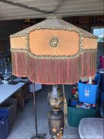 Close-up of a tall lamp with peach fringed fabric shade and chinoiserie urn base