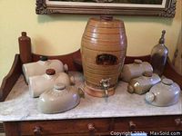 Overview of all pieces arranged on marble-topped sideboard: barrel, wood stand, six flasks, brown bottle, glass siphon