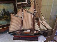 Close view of wooden Bluenose model ship with beige sails, rigging, and wooden base
