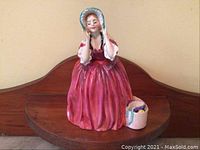 Front view of the figurine on wood shelf showing gown detail