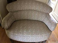 Front view showing curved backrest, rounded arms, and floral striped upholstery.