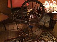 Full view of wooden spinning wheel with accessories set on rug