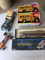 Overview of all lot items including the two new in box yellow toy school buses, one boxed Corgi TTC streetcar model, and two worn vintage die-cast toy cars.