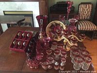 Wide view of ruby glass items arranged on table showing variety of pieces