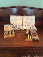 Wide view of all flatware and cutlery sets arranged on wood surface, showing original cases and boxed cutlery sets.