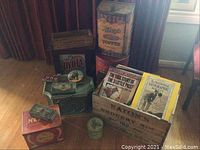 Overall view of wooden crates, tins and printed items on floor