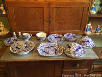 Overall view showing china pieces arranged on wooden sideboard including tureens, plates, bowls and accessories