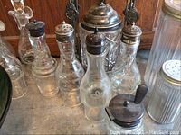 Group of clear glass cruets with metal tops, ribbed canister shaker and small mustard pot
