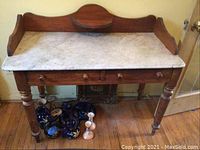 Front view of table showing marble top, three drawers and gallery backboard