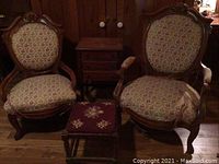 Two upholstered chairs flanking sewing table with footstool in front on wooden floor