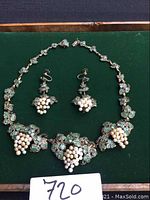 Full view of necklace and earrings laid on dark green background