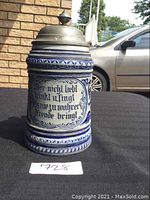 Front view of German stoneware tankard with pewter lid showing German text inscription and blue decorative scroll motifs