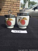 Two Royal Worcester egg coddles, small and large, showing peach fruit design on the front.